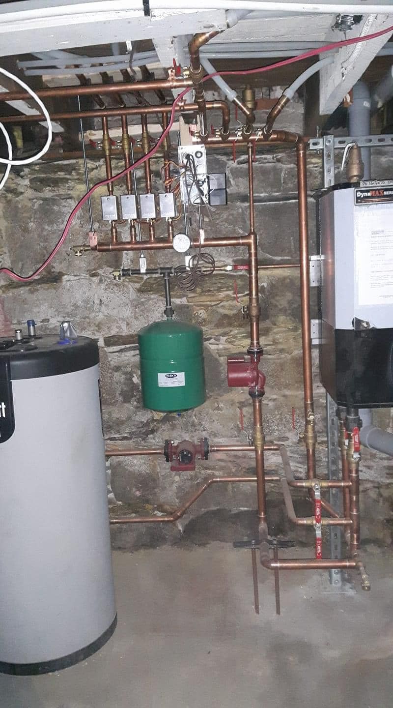 Copper piping, circulator pumps and boiler installed in a stone basement