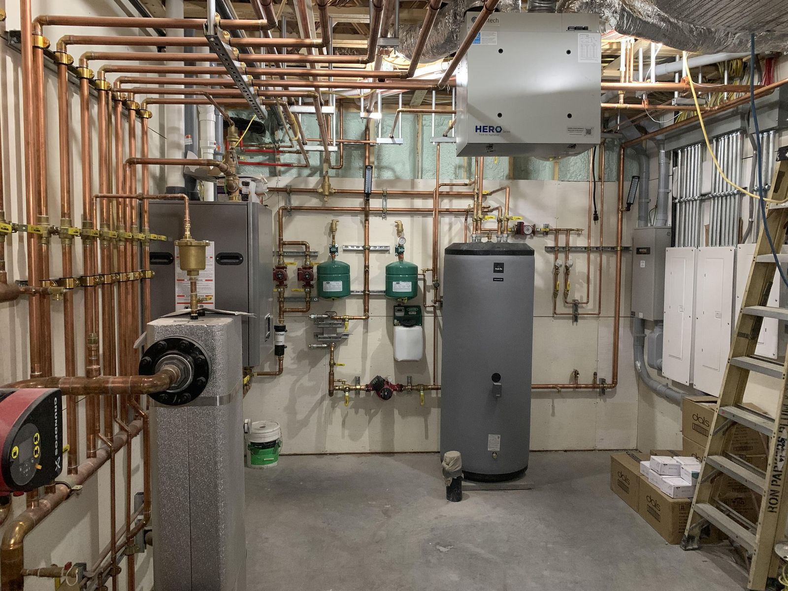 Neatly installed copper piping, boilers and hot water tank in a mechanical room