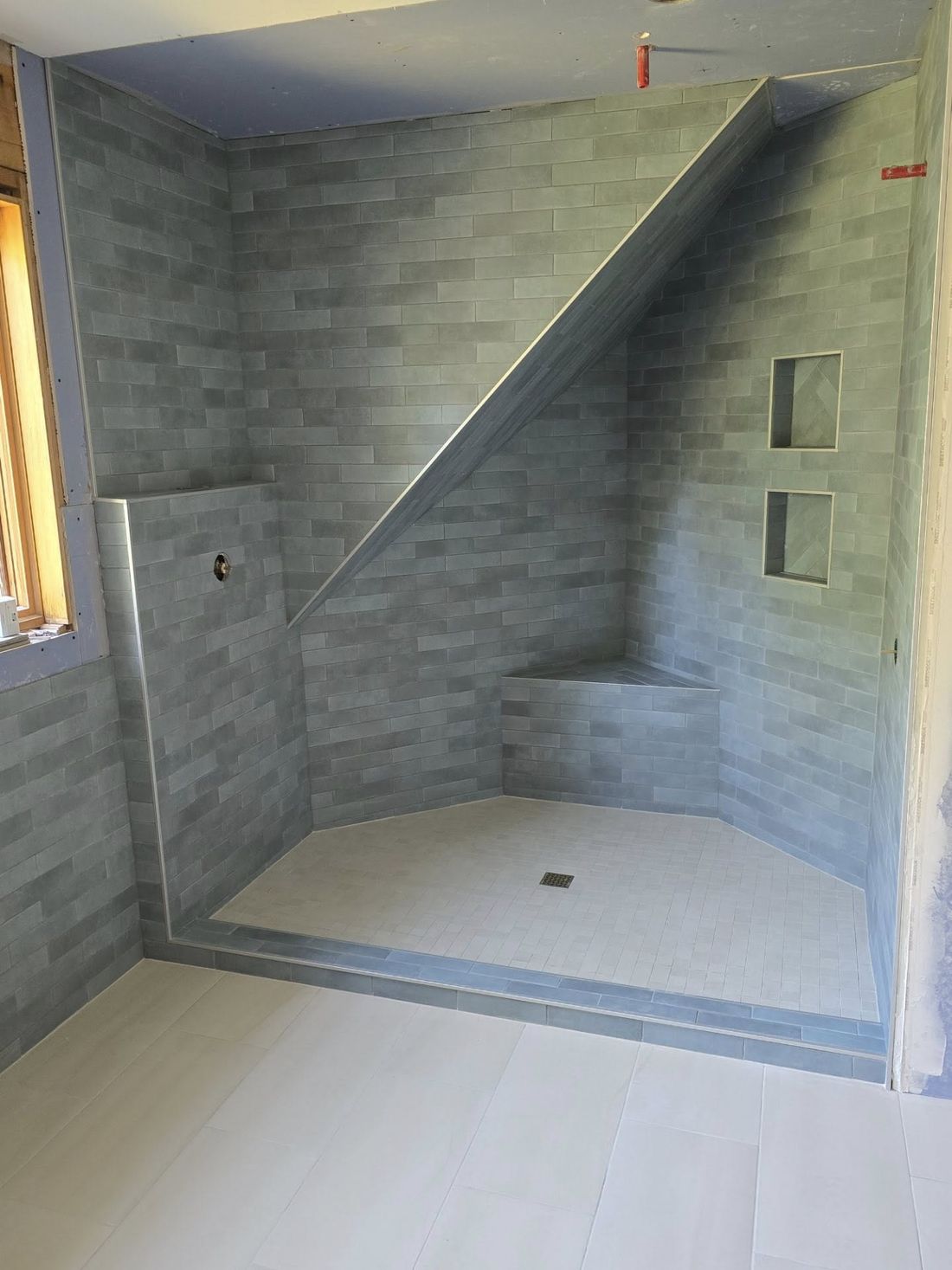 Custom tiled shower with recessed niches and a corner bench